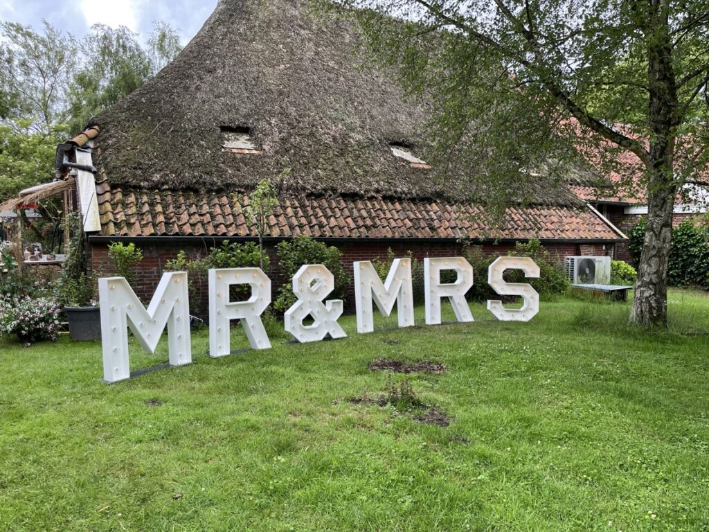 Grote verlichte MR & MRS-letters op een trouwlocatie
