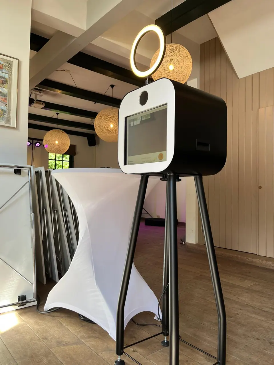 Photobooth met ringverlichting naast een statafel op een lichte evenementlocatie
